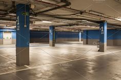 an empty parking garage with blue and gray paint on the walls, concrete floors and pillars