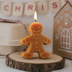 a gingerbread man candle sitting on top of a piece of wood next to a cake