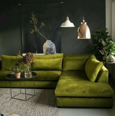 a living room with green couches and plants in vases on the coffee table