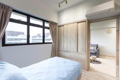 a bedroom with a bed, chair and large window in it's center area