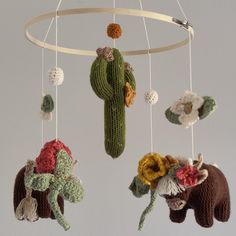 three crocheted animals hanging from a circular mobile with flowers and cactuses on it