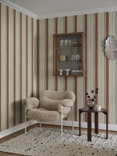 a living room with striped wallpaper and a chair in front of a small table