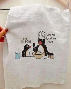 a person holding a white towel with two penguins on it and one penguin is eating from a bowl