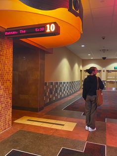 a woman is walking down the hall with her purse