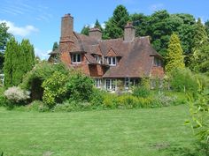 an old brick house surrounded by lush green grass and trees on a sunny day in the countryside