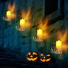 pumpkins lit up in front of a stone wall with flames coming out of them