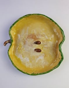 a yellow and green vegetable with two seeds in it's center on a white surface