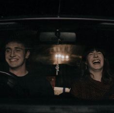 two people sitting in the back seat of a car with their mouths open and laughing