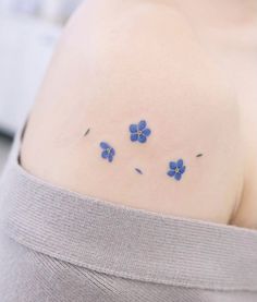 small blue flowers on the back of a woman's left shoulder and upper arm