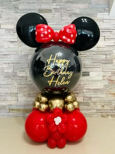 a mickey mouse balloon with a red bow on top