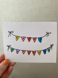 a hand holding up a card with colored hearts and buntings on it's string