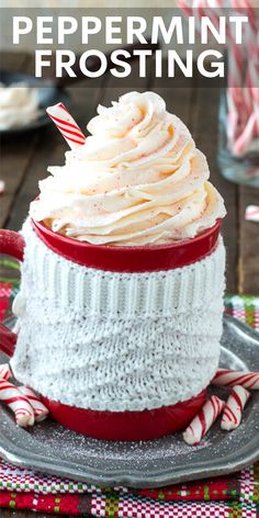 a red and white cup with whipped cream in it on a plate next to candy canes