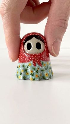 a hand is holding a small figurine with eyes