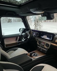 the interior of a mercedes benz vehicle with snow covered trees in the background