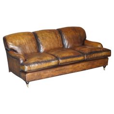 a brown leather couch sitting on top of a white floor next to a wooden frame