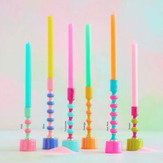 there are many different colored candles in the same row and one is pink, blue, green, yellow, orange