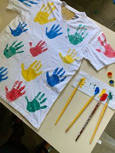 a t - shirt with handprints on it next to paintbrushes