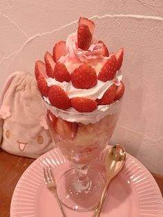 a dessert with strawberries and whipped cream in a glass dish on a pink plate