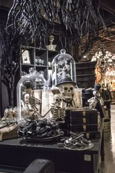 an assortment of skeleton figurines on display in a store with glass domes and chains hanging from the ceiling