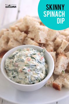 spinach dip in a small white bowl on a plate with crackers and bread