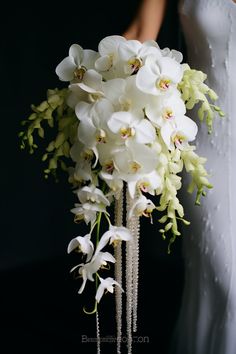 the bride's bouquet is made up of white orchids and greenery, along with pearls