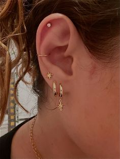 a close up of a person's ear with gold stars on it and a chain around the ear