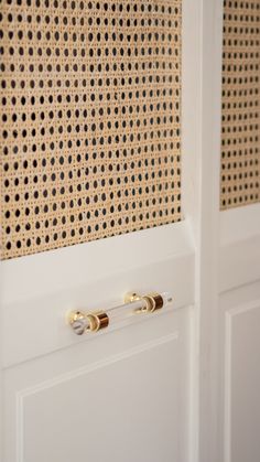 two white doors with gold handles on each side and a perfored wall behind them