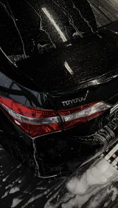 a black car is parked on the side of the road covered in snow and ice