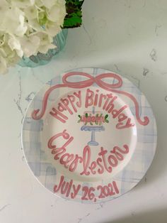 a happy birthday plate on a table next to flowers