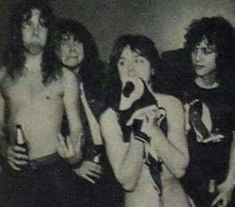 an old black and white photo of four people posing for the camera with one woman holding a microphone