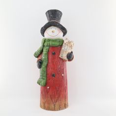 a snowman figurine with a green scarf and top hat holding a book