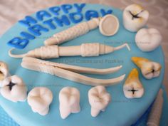 a birthday cake decorated with dental instruments and icing on top of blue frosting