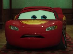 a red car with big eyes sitting on the floor