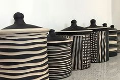 several black and white vases lined up against a wall