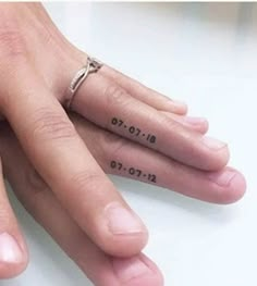 two people's hands with wedding rings on their fingers and numbers tattooed on them