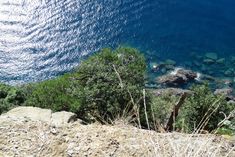 the water is crystal blue and clear on this sunny day, with rocks in the foreground