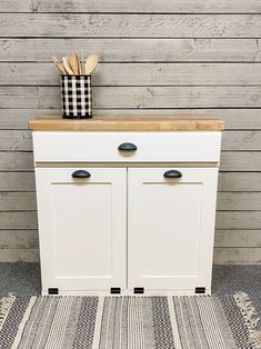 a white cabinet with two doors and some wooden utensils on top of it