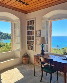 a room with two windows and a desk in front of the window is an ocean view