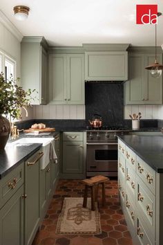 a kitchen with green cabinets and black counter tops, an area rug on the floor