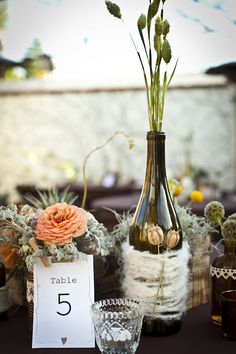 the table is set with vases, flowers and cards for guests to write on