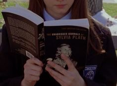 a girl is reading a book in the park