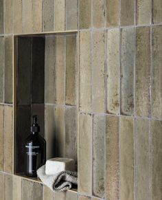 a bathroom with a mirror, soap dispenser and towel on the shelf