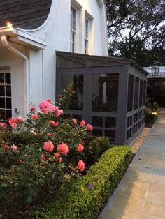 a small white house with pink flowers in the front yard