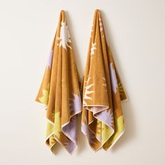 two yellow and purple towels hanging on the wall next to each other, one is folded up