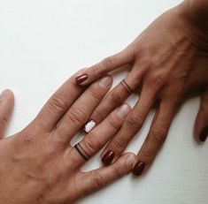 two people with their hands together holding each other's wedding rings and engagement bands