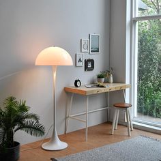 a white lamp sitting on top of a wooden table next to a desk and chair