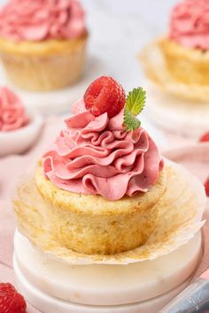 a cupcake with pink frosting and raspberries on top