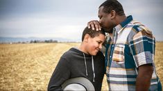 two men standing in the middle of an open field, one is holding his head