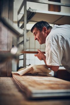 a man in a white shirt is making pizza dough