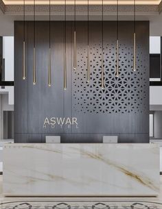 the front desk of aswar is surrounded by white marble and gold accents, with chandeliers hanging from the ceiling